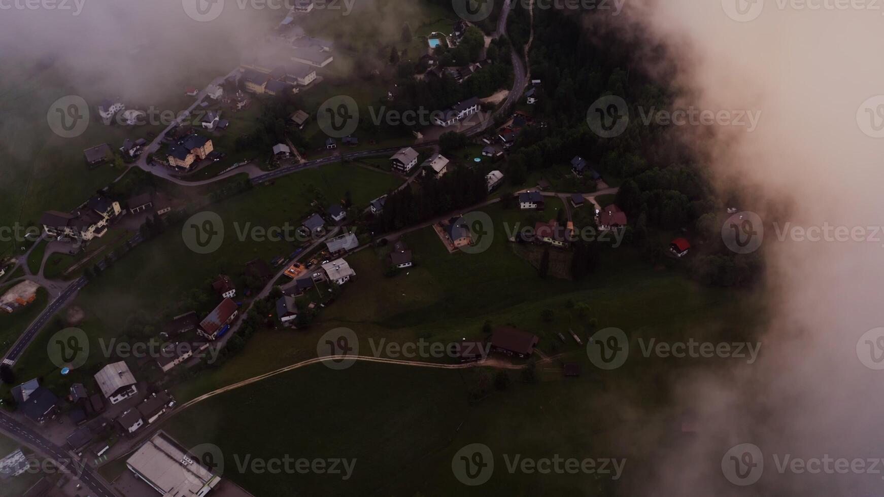 The drone flies high above the clouds, offering a view of the village at the foot of the Alps. filming in the evening from a bird's eye view. Austria, Alps photo