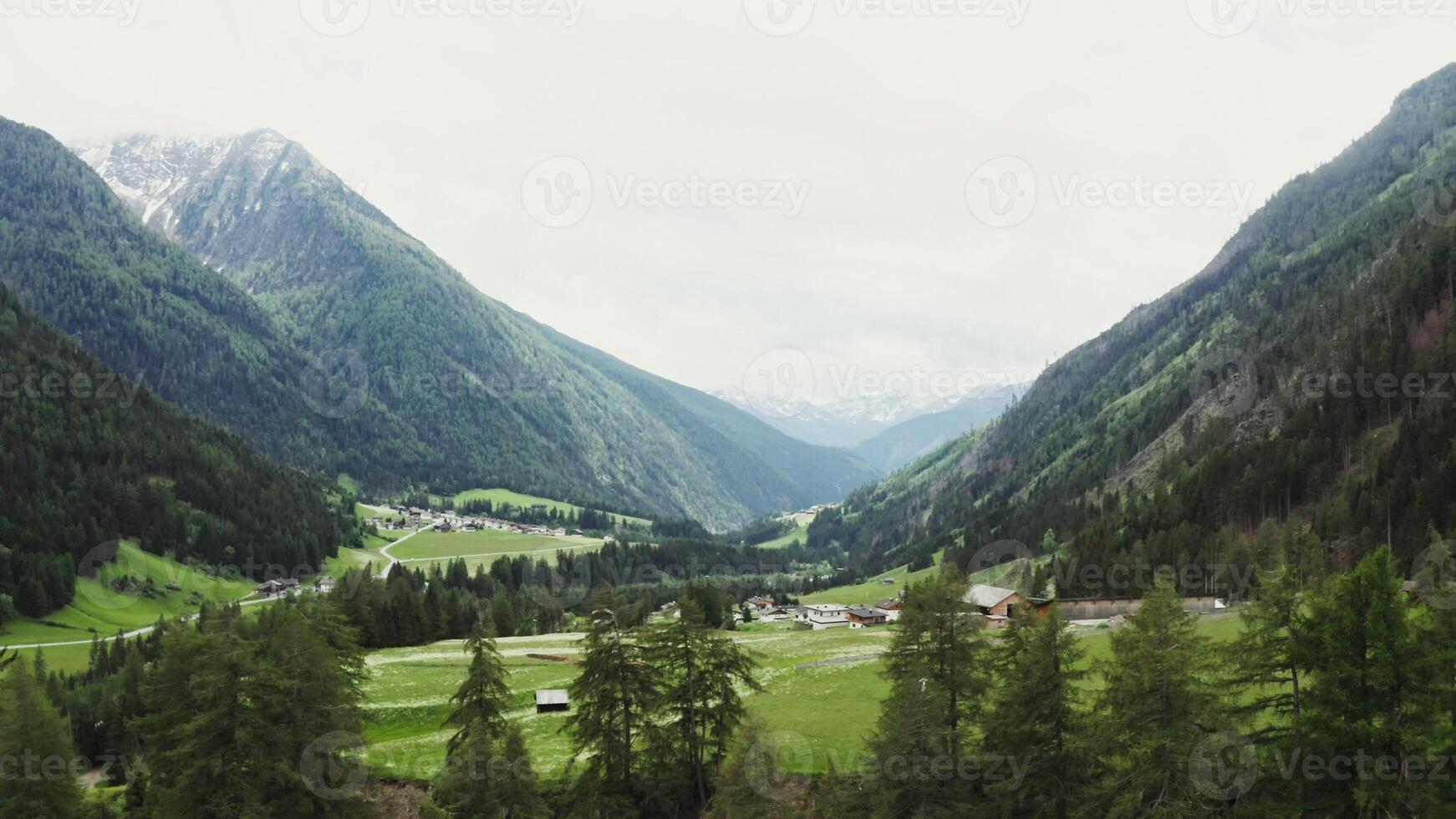Beautiful panormany view of the high mountain valley with the village in the lowland. The peaks of the rocky Alpine mountains are covered with snow. Austria - mountain photo