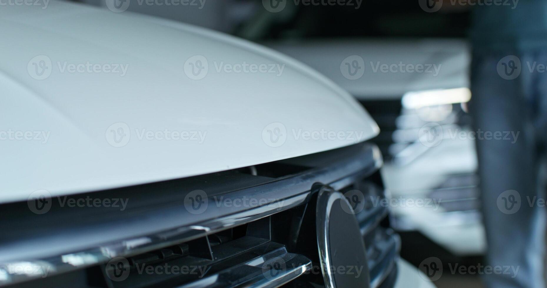 The car dealership manager is talking to the customer standing next to the car. He opened the hood of the car, Close-up of his hands, unrecognizable persons photo