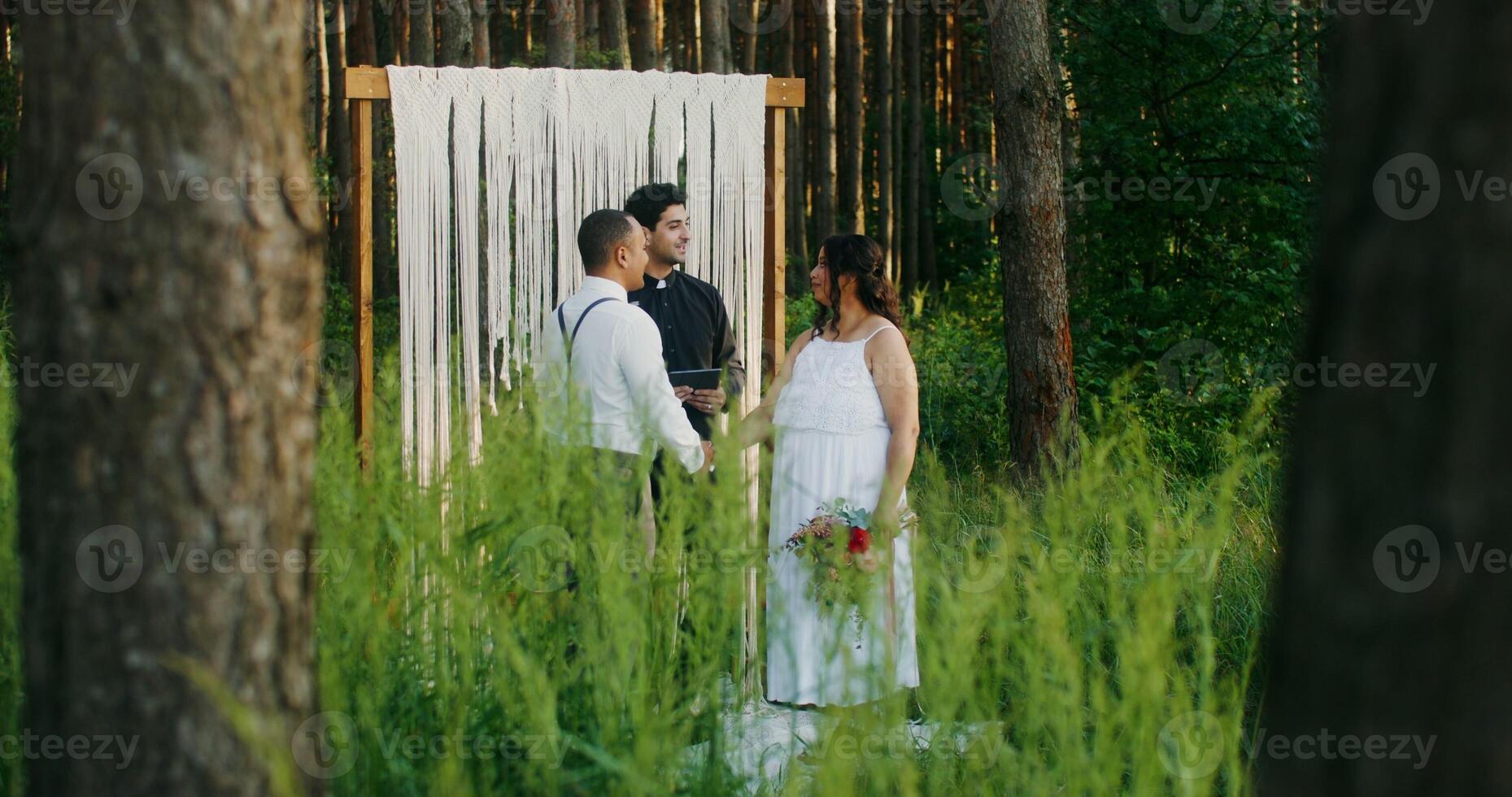 The bride and groom of African-American appearance hold hands standing in front of the altar at an outdoor wedding - wedding photo