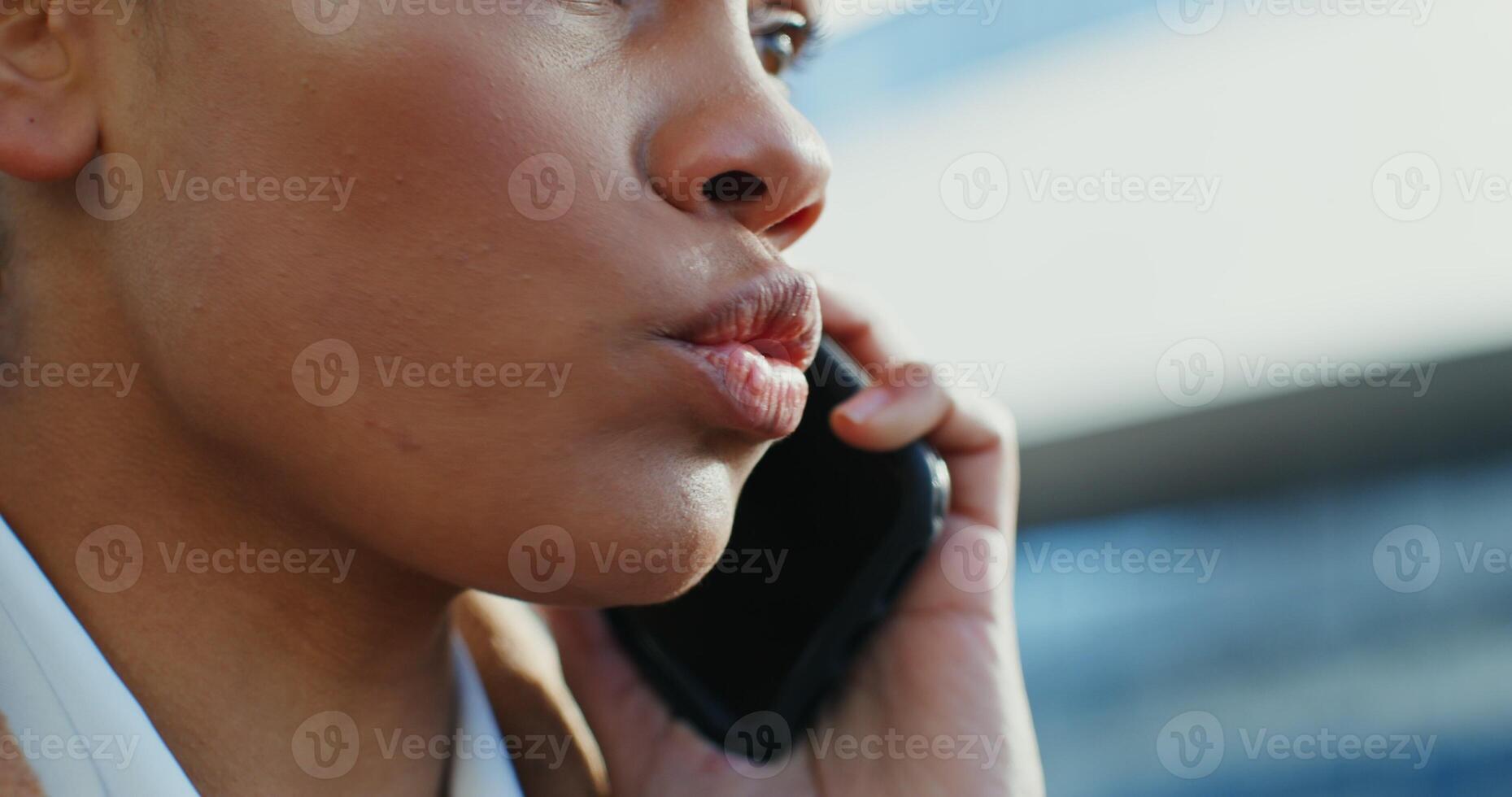 Beautiful young african american woman swearing while talking on a mobile phone outdoors, close-up photo