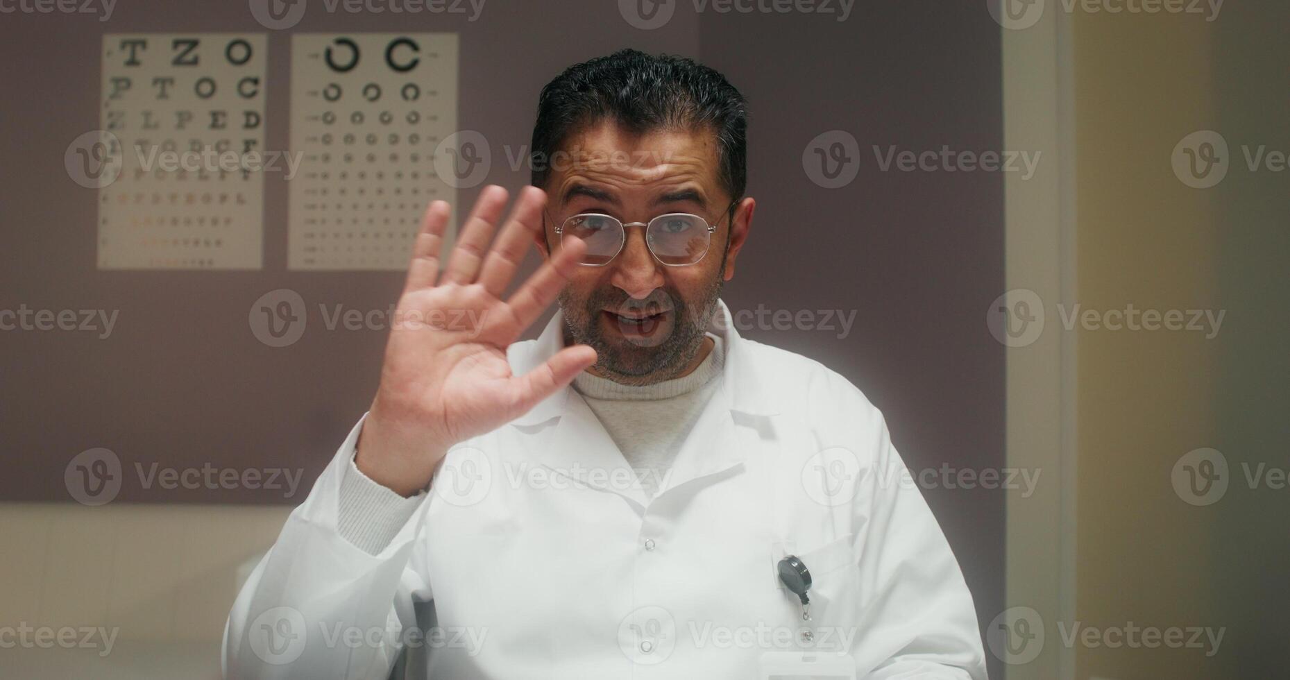 The doctor smiles and talks looking at the camera as if at a laptop screen during a online chat at the clinic photo