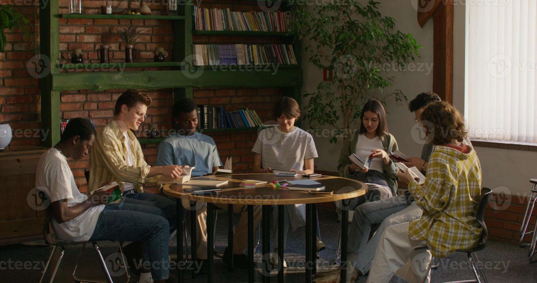 A man is talking to his friends while sitting at a table indoors. He opens the Bible. Bible Study Club - sitting photo