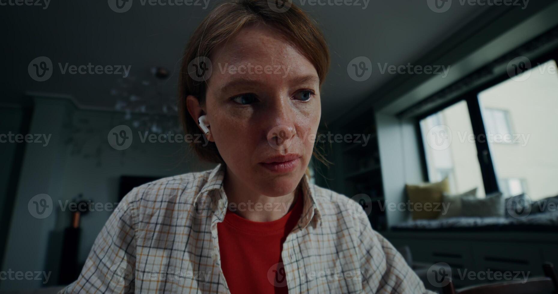 A young woman in casual clothes makes notes in a notebook sitting in front of an open laptop in a stylish home interior, with a serious look - notebook photo