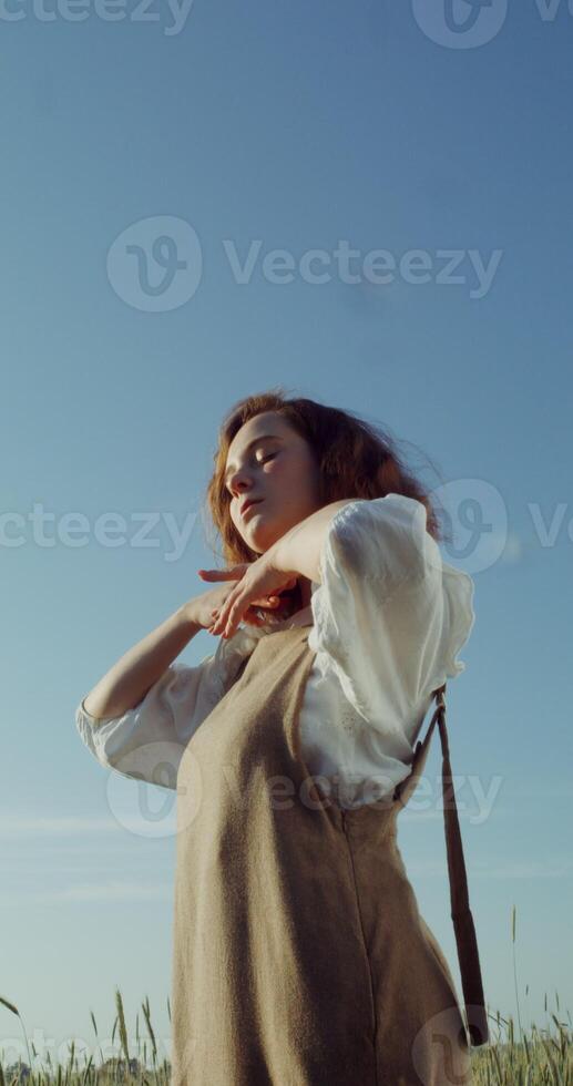 A young beautiful woman dances, smoothly moving her hands and closing her eyes in pleasure, posing for a photo shoot in a wheat field among the ears. 4k vertical , red komodo - moving