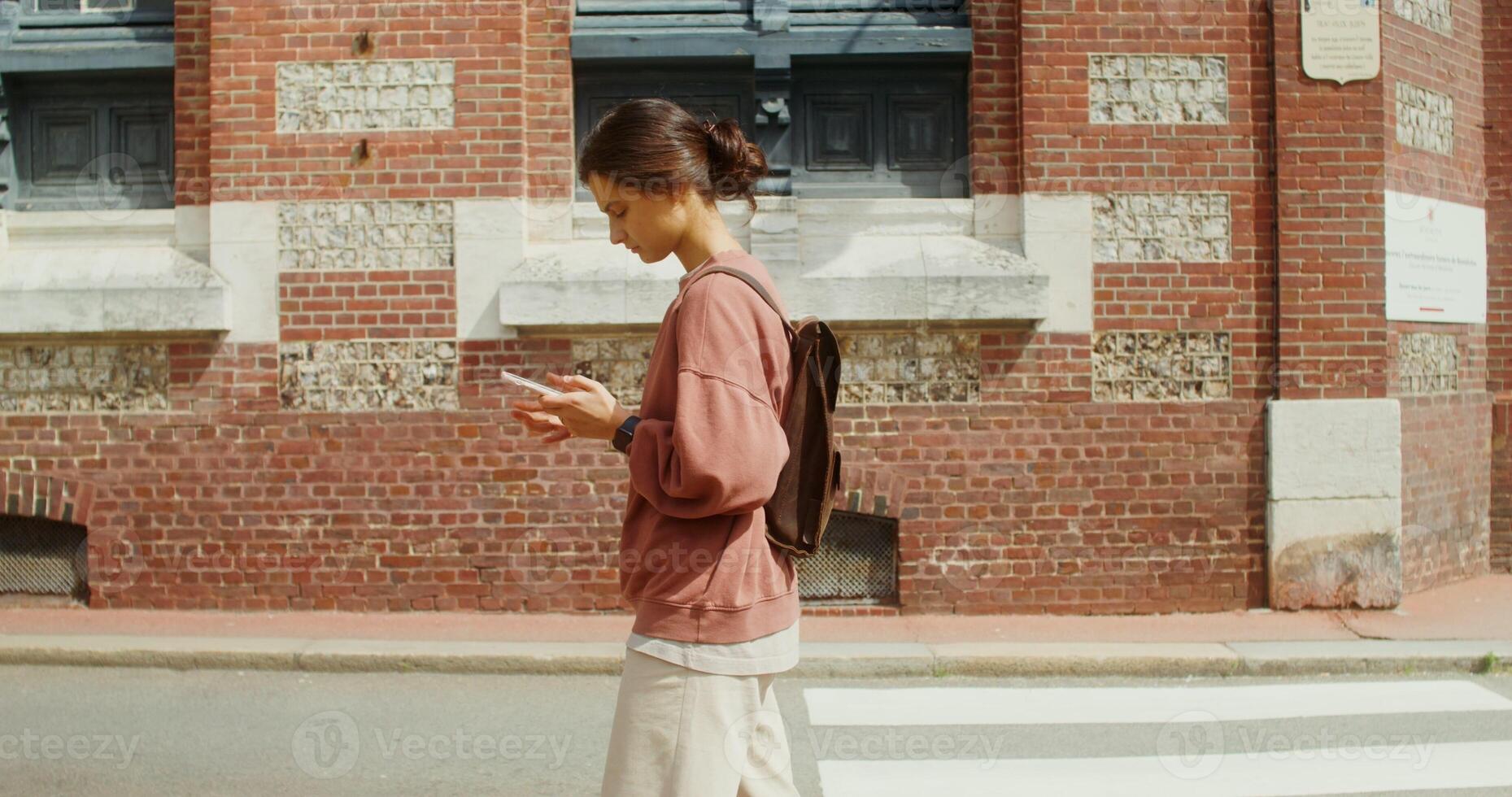 A beautiful young woman uses a smartphone while walking around a beautiful European city with traditional houses. F camp, France. 4k , red komodo photo