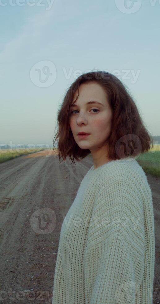 Close-up of the face of a young red-haired woman with a short haircut, looking at the camera and up with a serious look, standing against a blue sky. 4k , red komodo. - serious photo