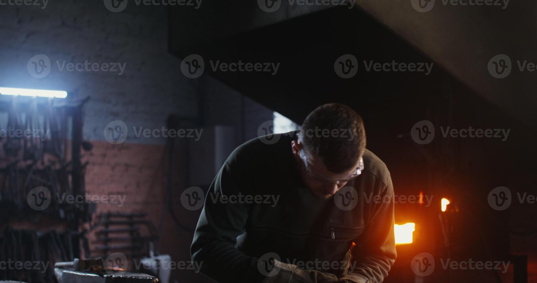 A young man of European appearance, dressed in work clothes and goggles, cuts a sheet of iron with a plasma cutter while working in a forge. 4k, red komodo - clothes photo