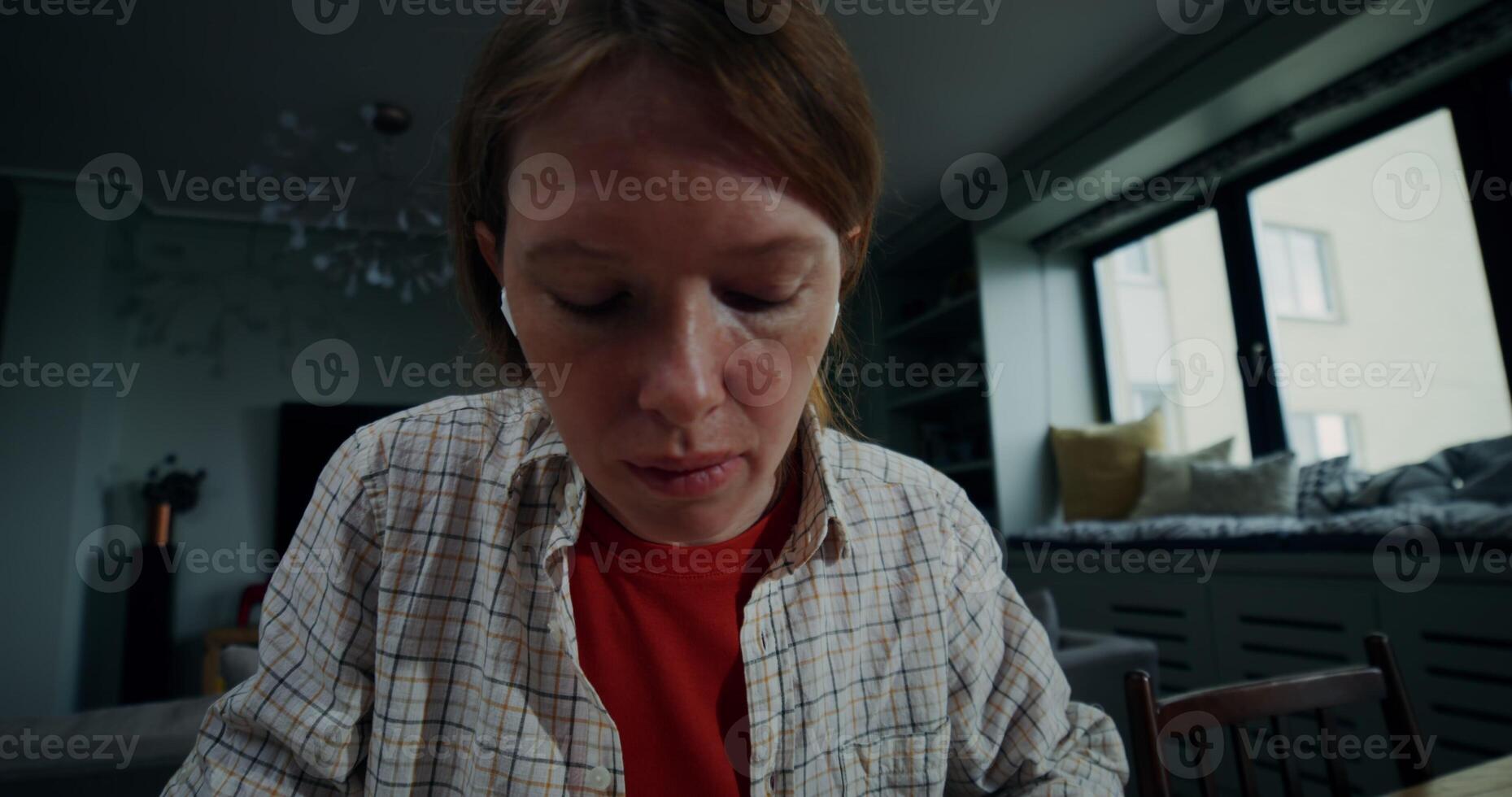 A young woman in casual clothes makes notes in a notebook, and uses a laptop while sitting at a table in a stylish home interior with a serious look - laptop photo