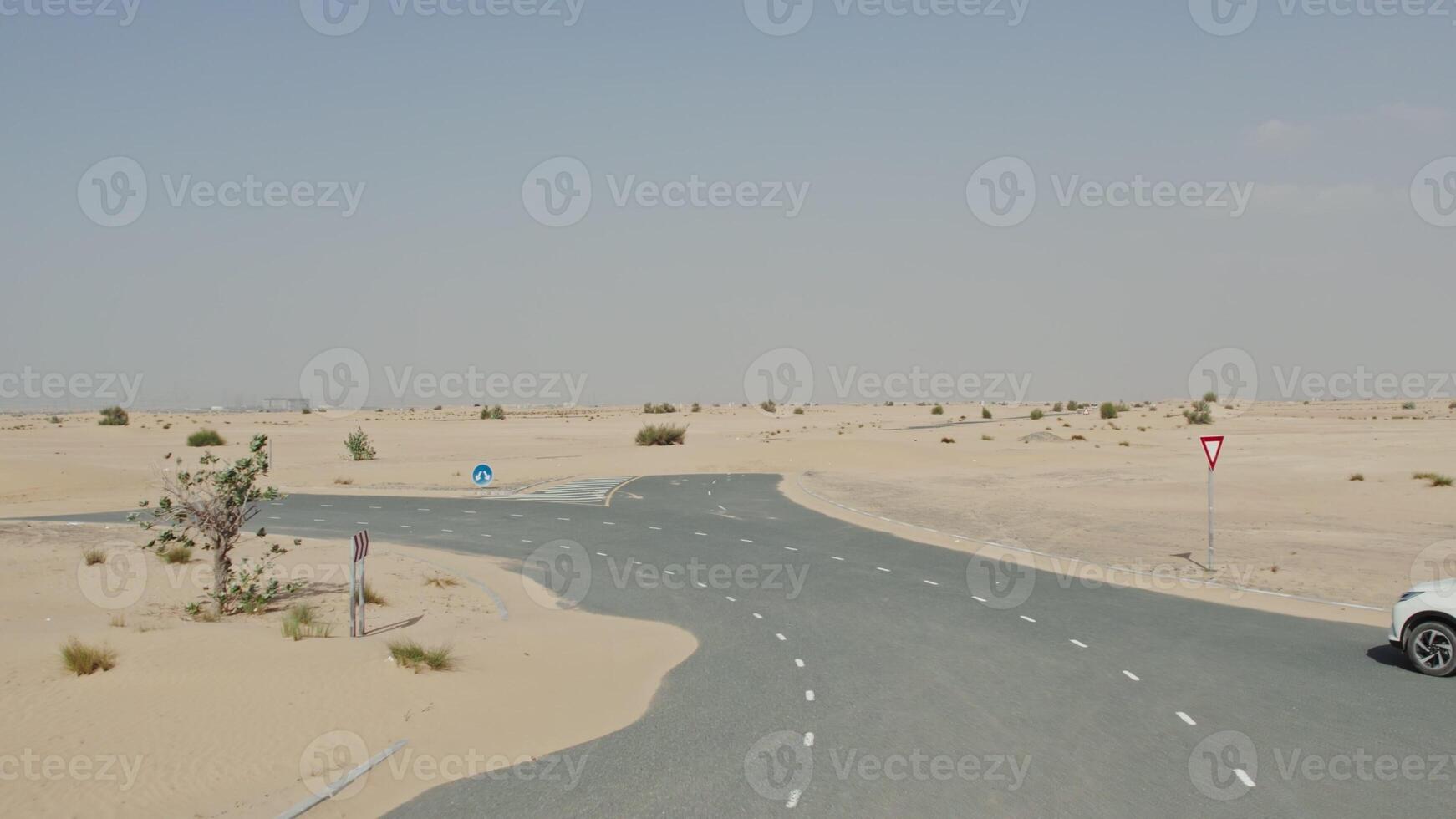 Drone view of a white SUV driving along a modern paved road covered with desert sand photo