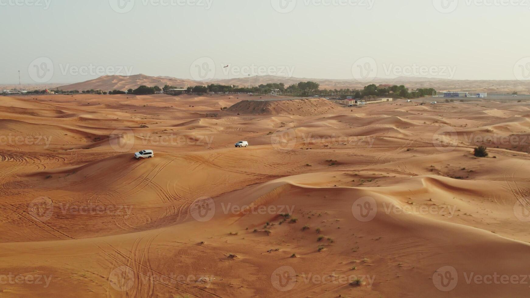 Cars drive off-road on the red sand dunes of the desert with sparse vegetation among the sand, drone - vegetation photo