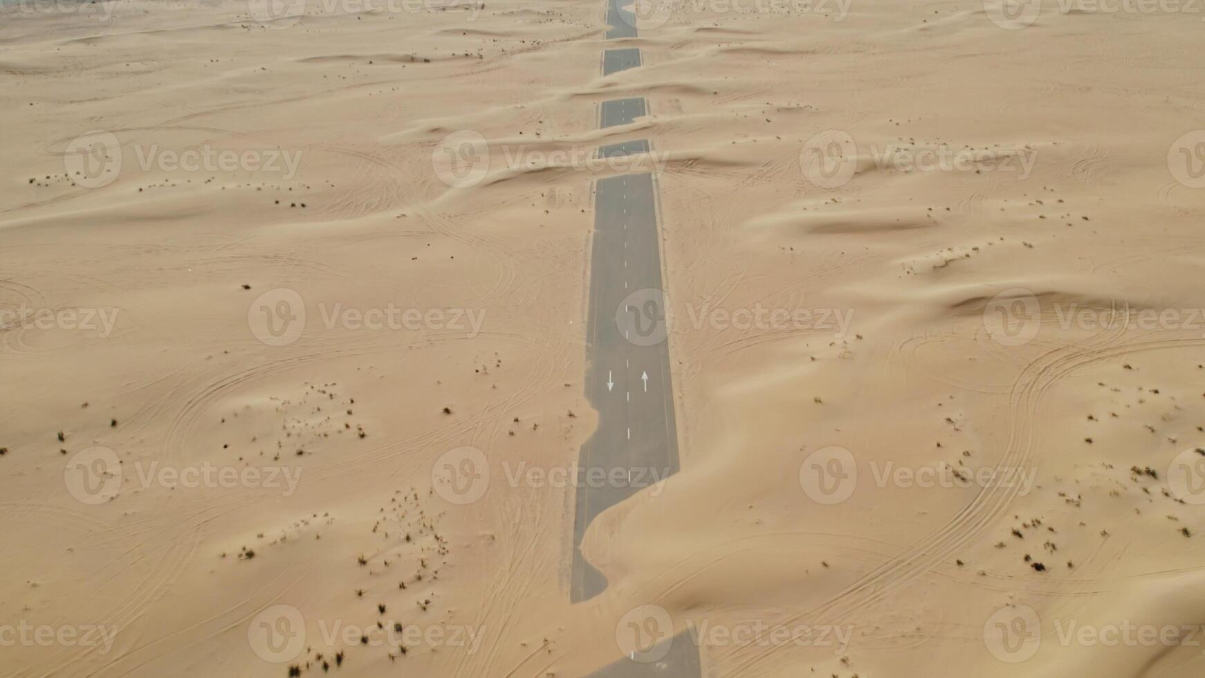 Top view of a modern paved road covered with sand, laid in the middle of the desert photo