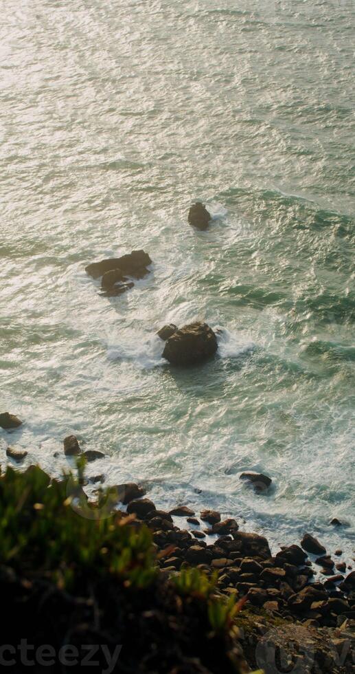Top view of the rocky seashore, foamy waves beating against rocks, reef in shallow water photo