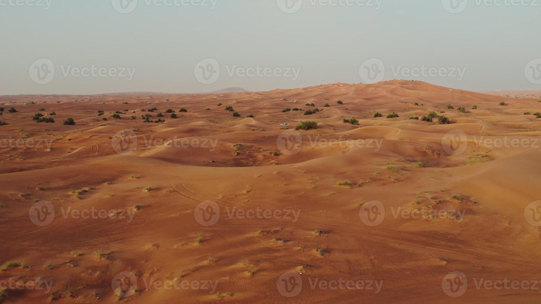 Drone view of a lifeless desert with sparse vegetation and off-road cars photo
