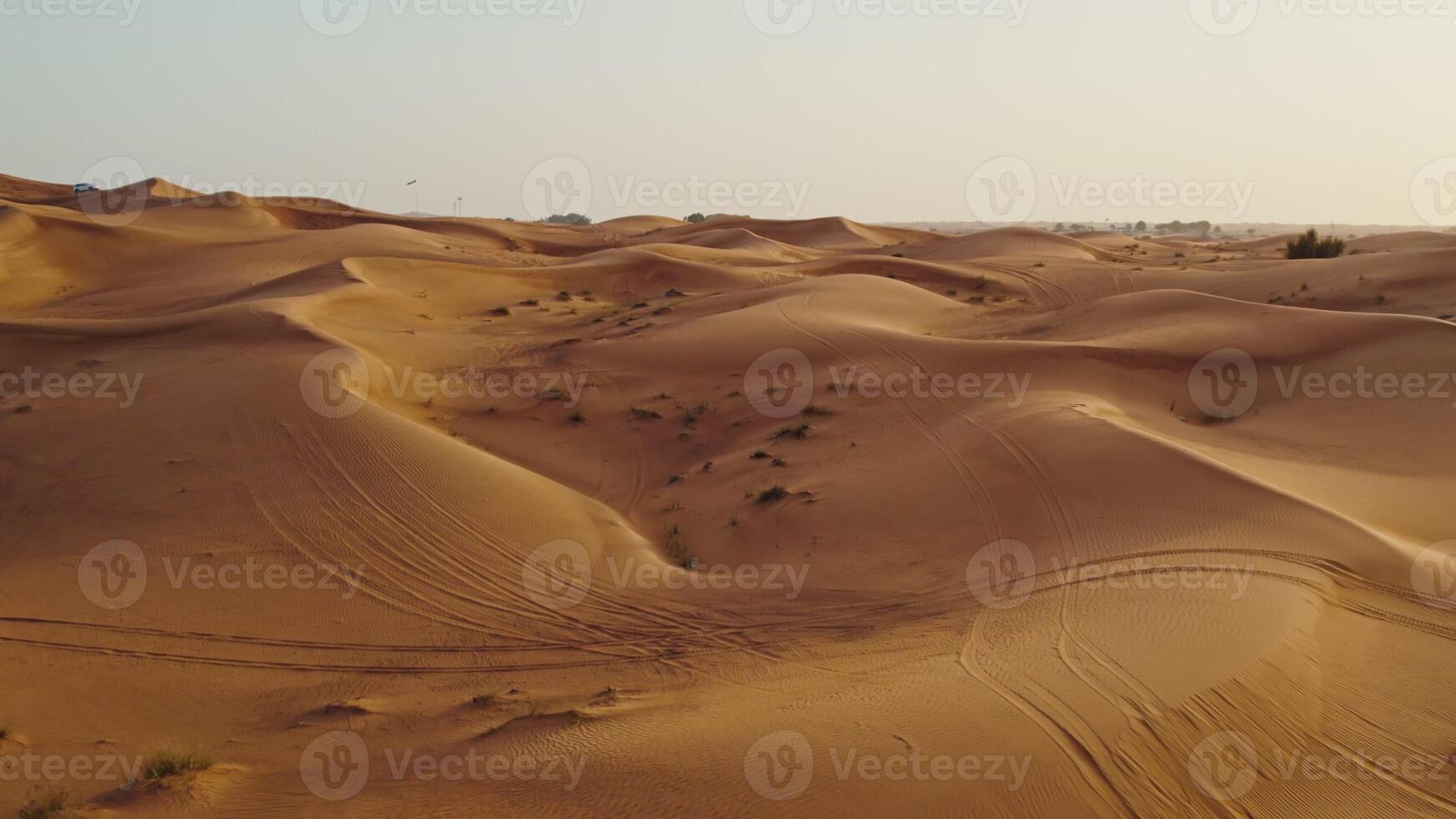 A bird's-eye view from a drone of sand dunes with traces of cars engaged in off-road driving, and sparse vegetation among the sand - vegetation photo