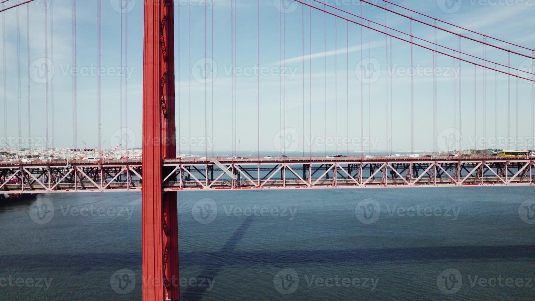 Drone view of the red suspension bridge over the river. The drone flies parallel to the bridge photo