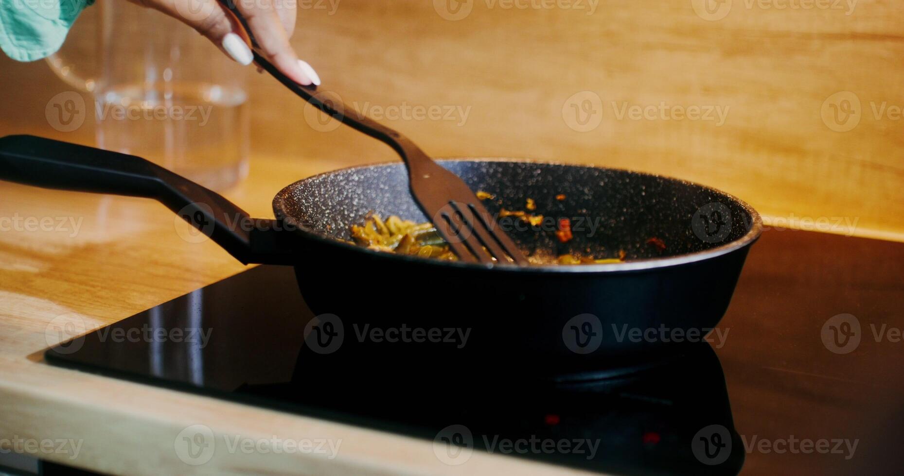 Close-up of a frying pan during cooking. A woman's hand stirs the string beans with a spatula - string photo
