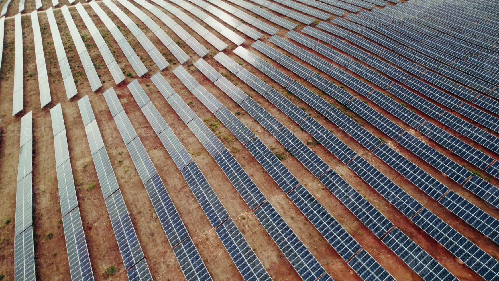 A lot of solar panels lie in straight lines on a deserted land, a bird's-eye view from a drone photo