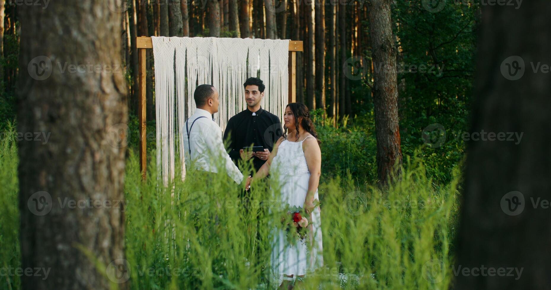 The bride and groom of African-American appearance hold hands standing in front of the altar at an outdoor wedding - outdoor photo