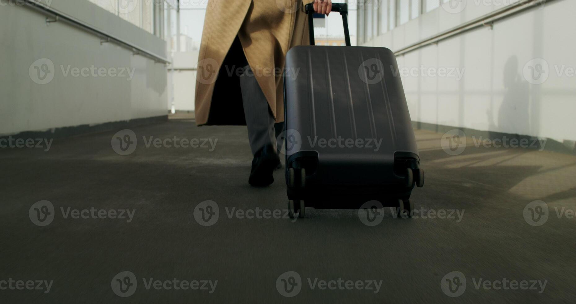 A woman in a coat with luggage in her hand walks down the corridor of a public building, close-up of her legs, an unrecognizable person - public photo