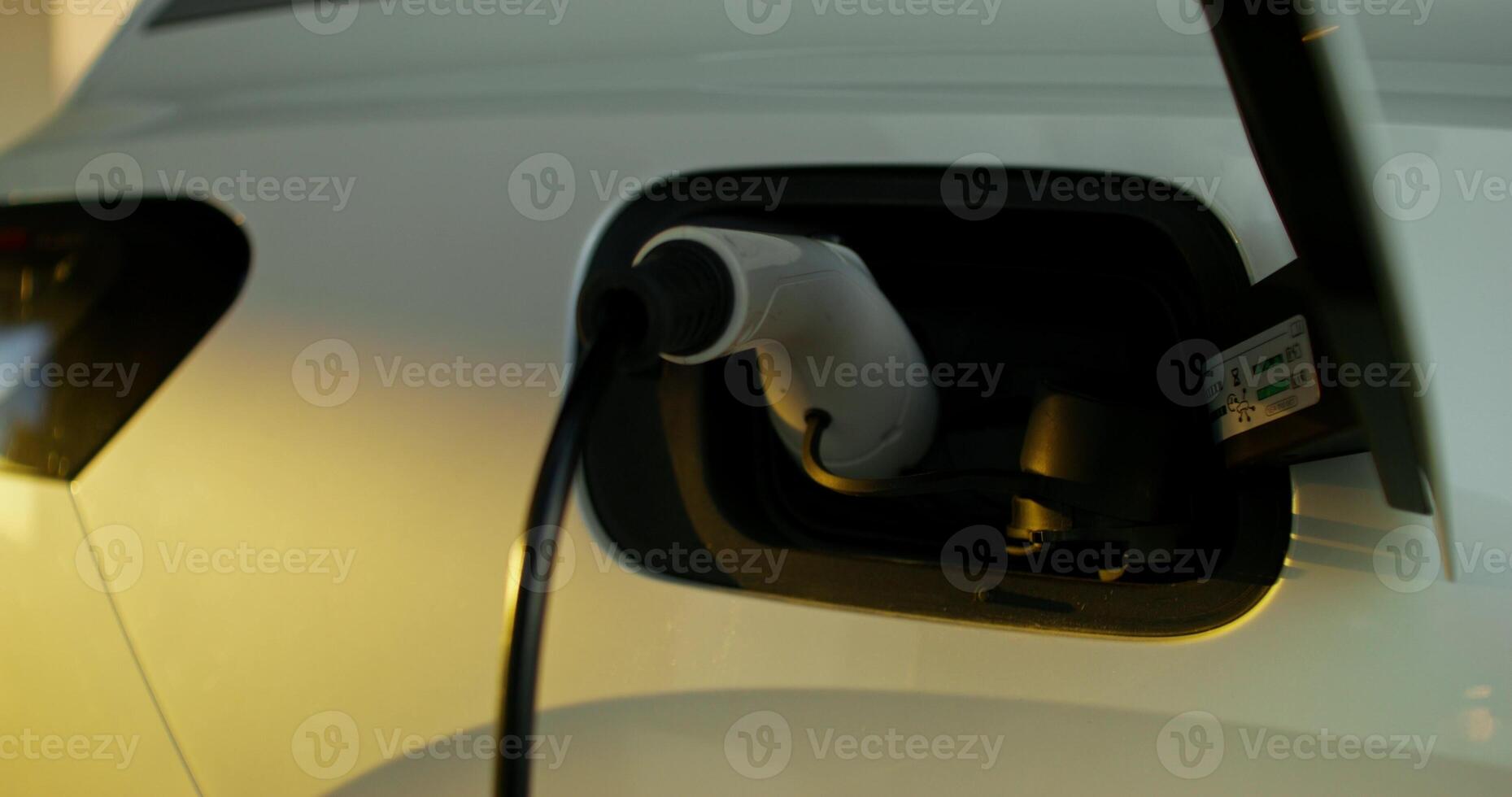 A white electric car on a charge, close-up of the cable in the connector photo