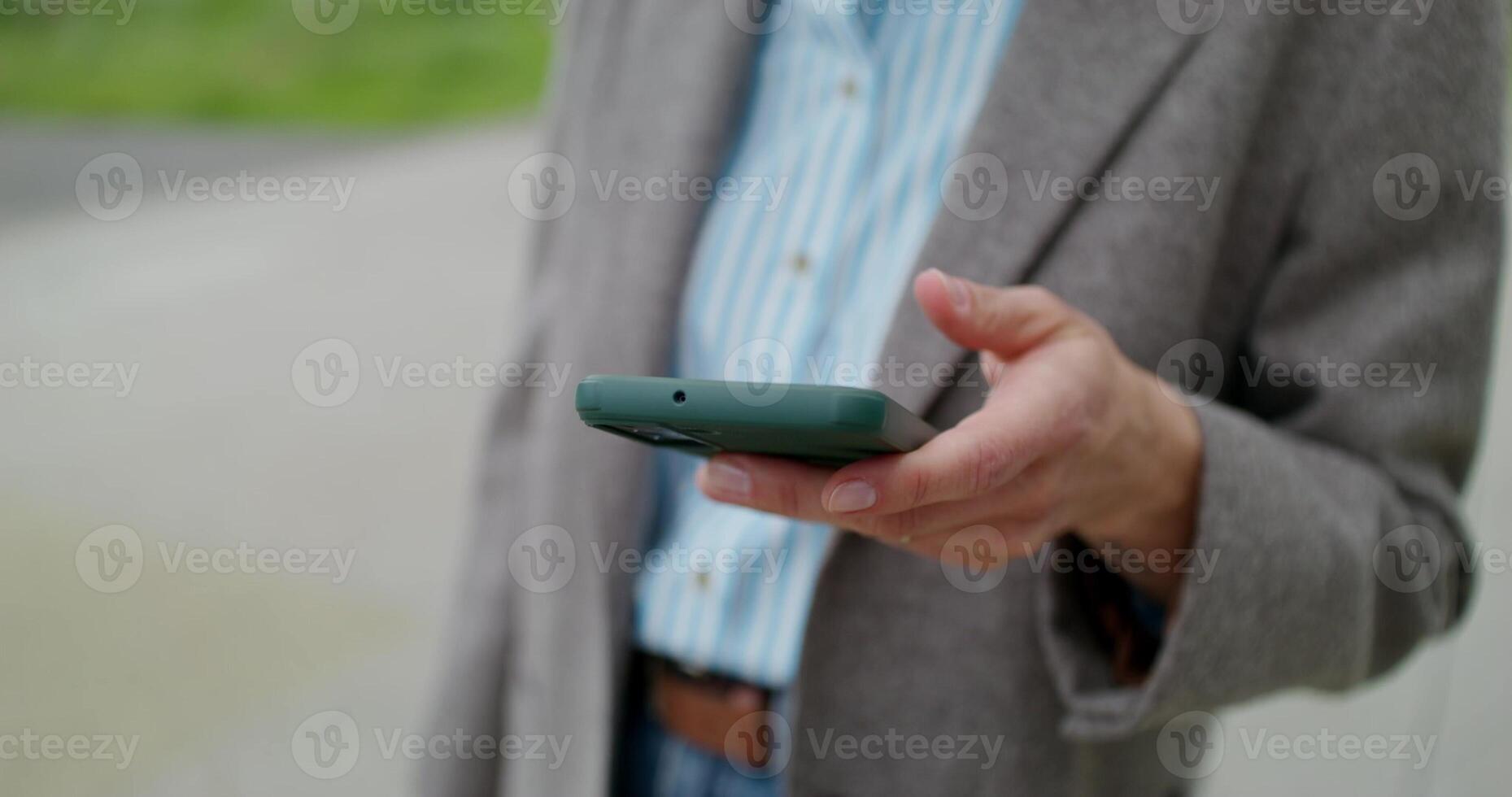 A woman uses a mobile phone while standing outdoors in sunny. day, Close-up of her hand, unrecognizable person photo