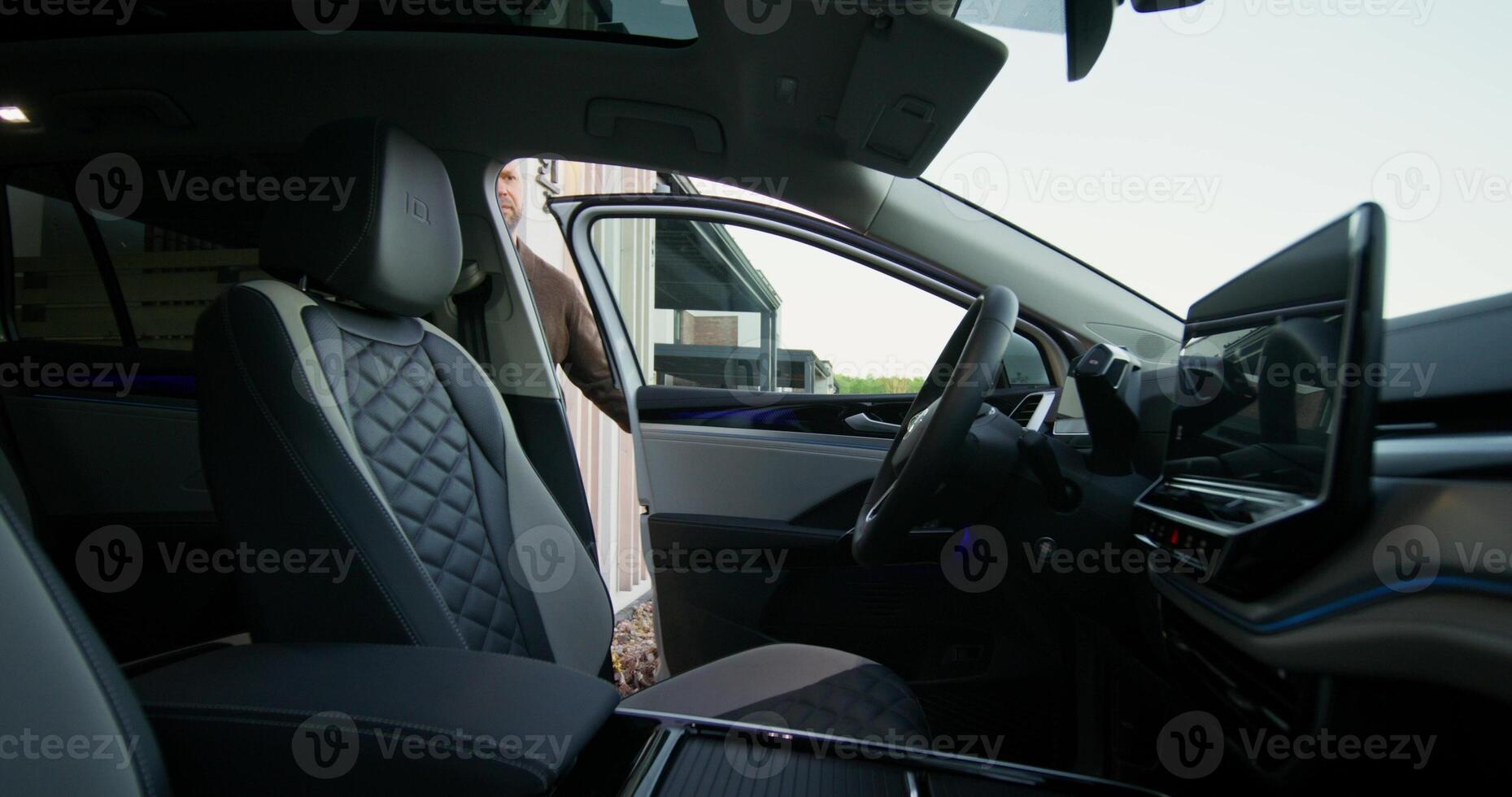 The man opens the car and sits in the driver's seat. View from the car interior photo