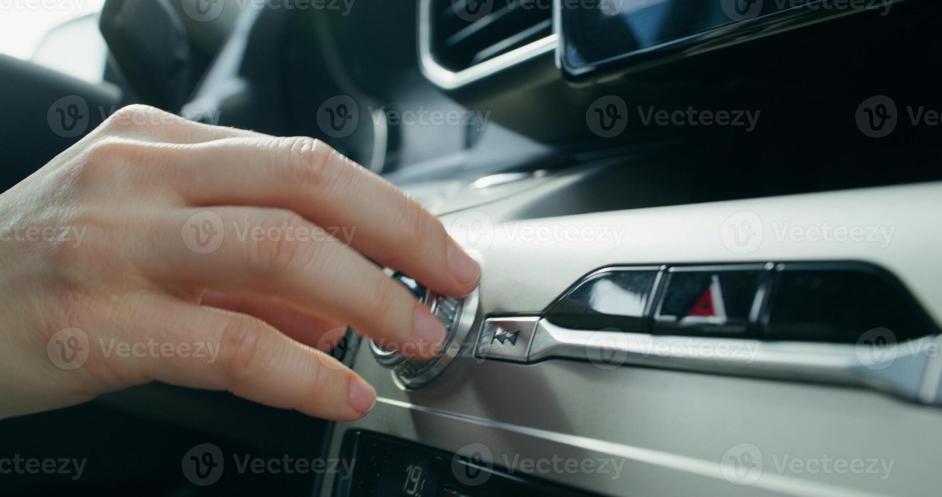 A woman's hand turns the volume control lever in the car's audio player while driving, an unrecognizable person - player photo