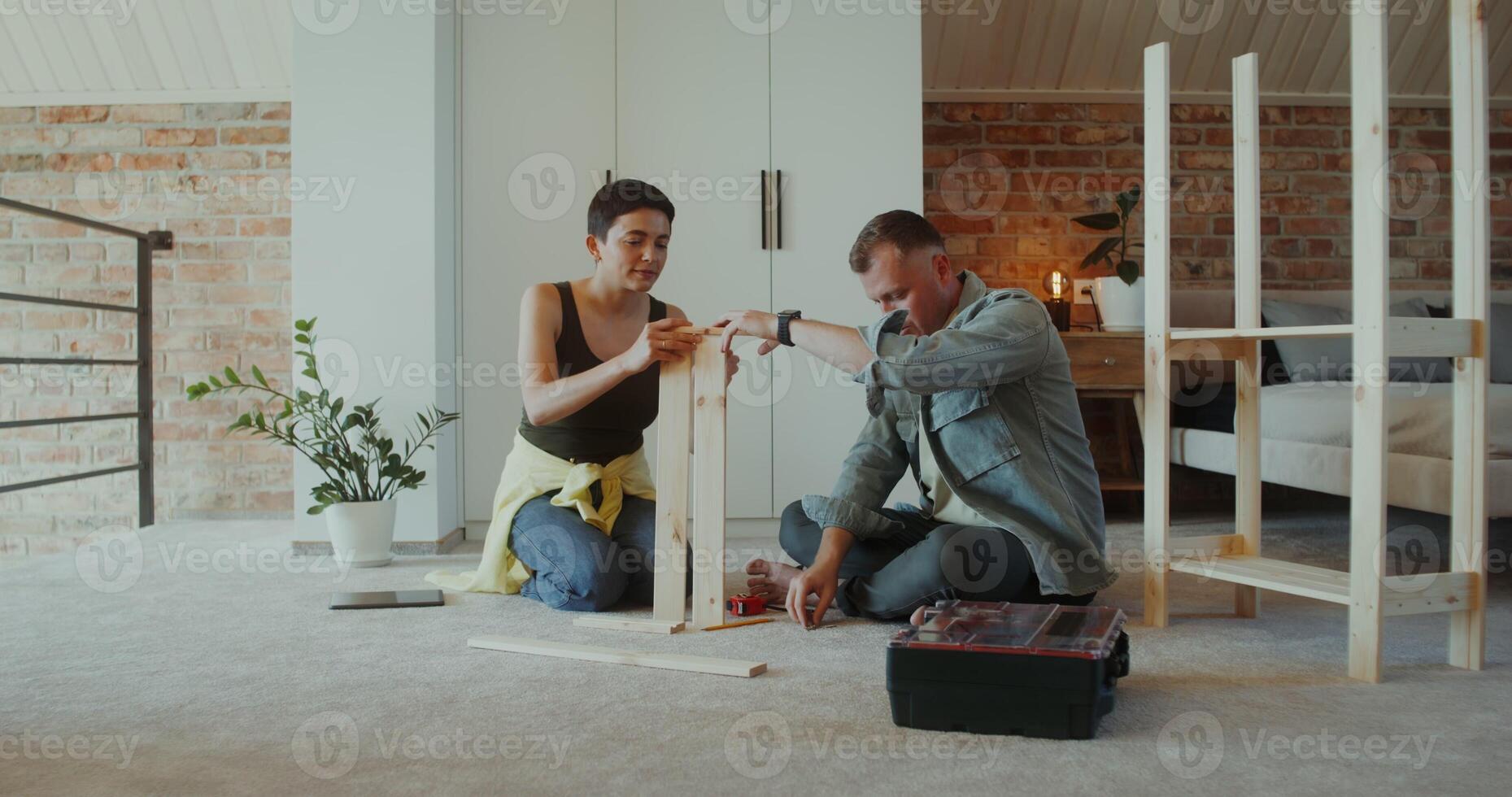 A man and a woman assemble a shelving at home, they use a screwdriver, talk and smile sitting on the floor - sitting photo