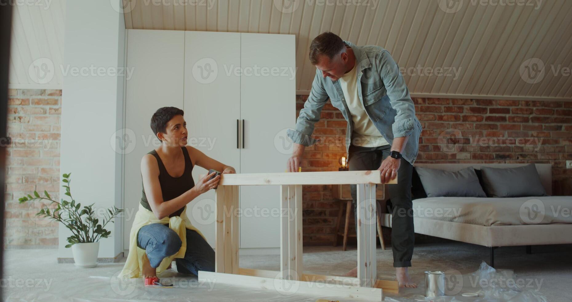 A man and a woman polish a rack with sandpaper in a stylish home interior, they smile and talk - polish photo