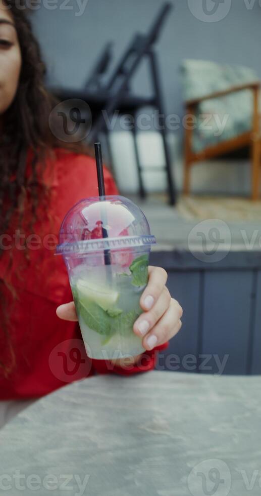 A young woman in casual clothes eats a burger and drinks a mojito while sitting in a cafe - burger photo