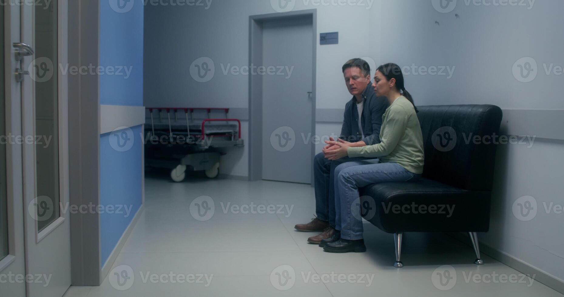 Concerned patient's relatives are waiting sitting on the couch in the hospital corridor - hospital photo