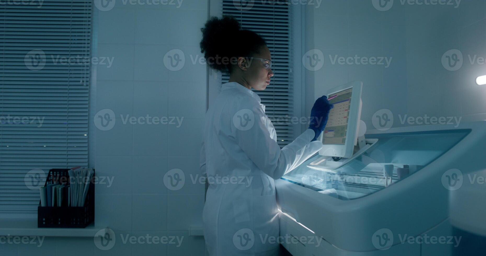 Work in a medical laboratory. A man and a woman are talking using a laptop sitting at a table with a microscope. A woman sets up a blood splitting device photo