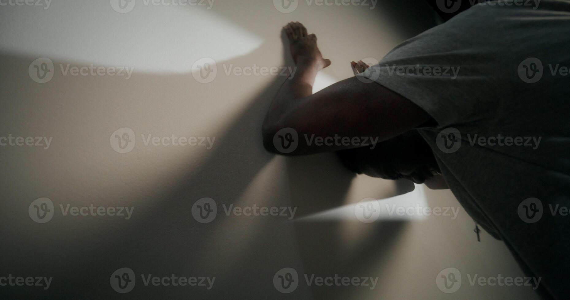 A bearded man in casual clothes screams and punches against the wall out of anger standing indoors - screams photo