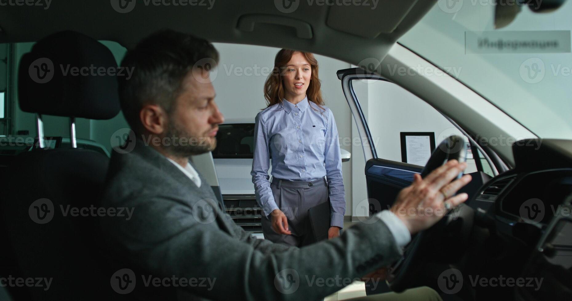 A man and woman in a car looking at a car photo