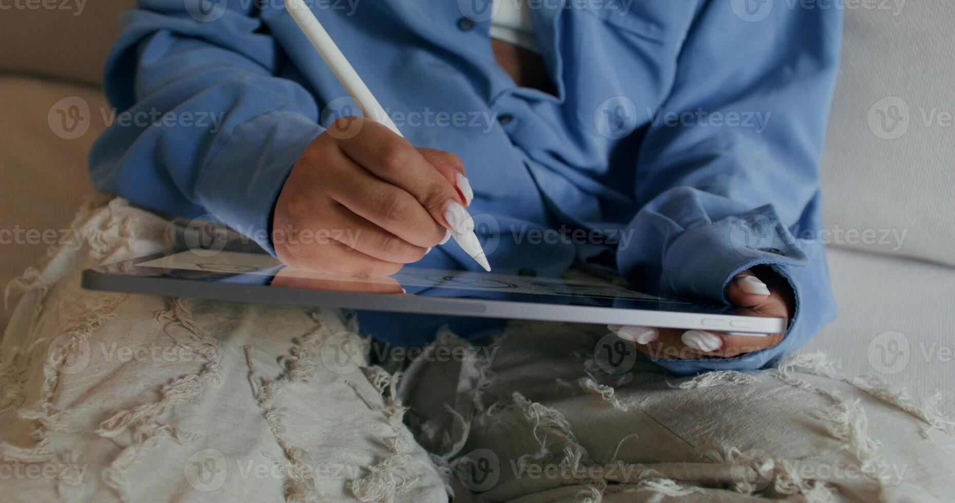 A person sitting on a couch holding a tablet photo