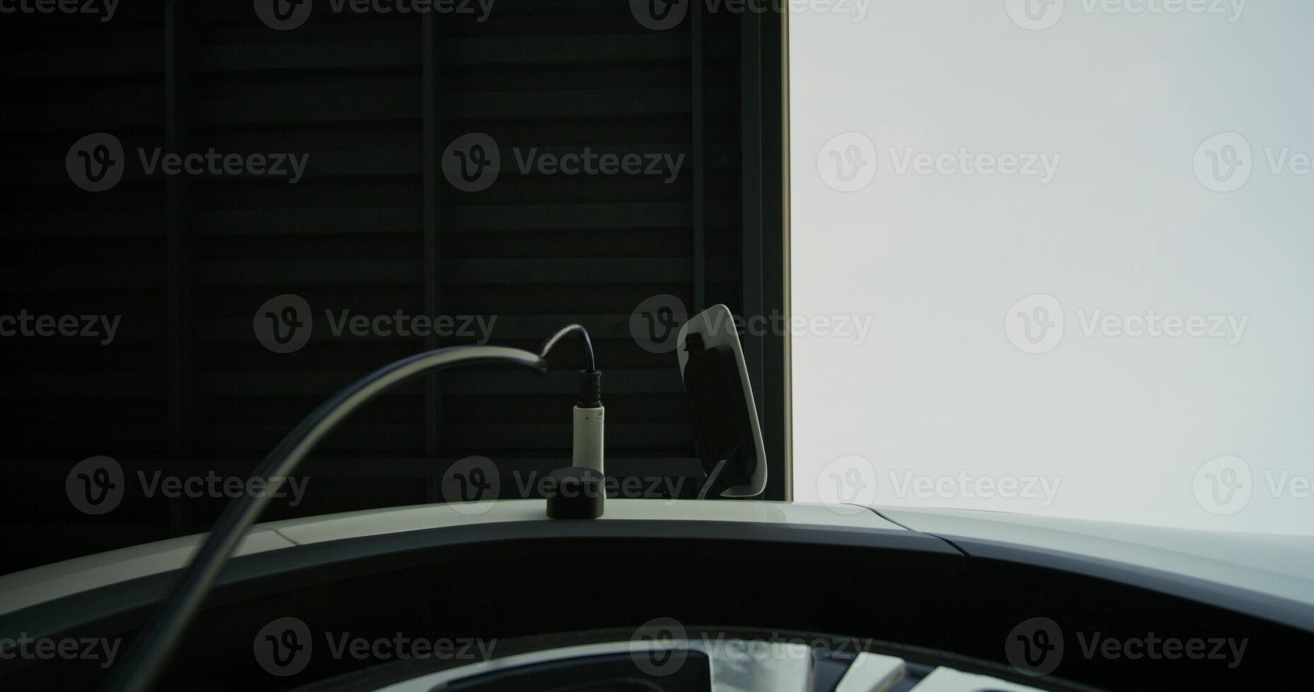 A man in casual clothes disconnects charging from an electric car, bottom view photo