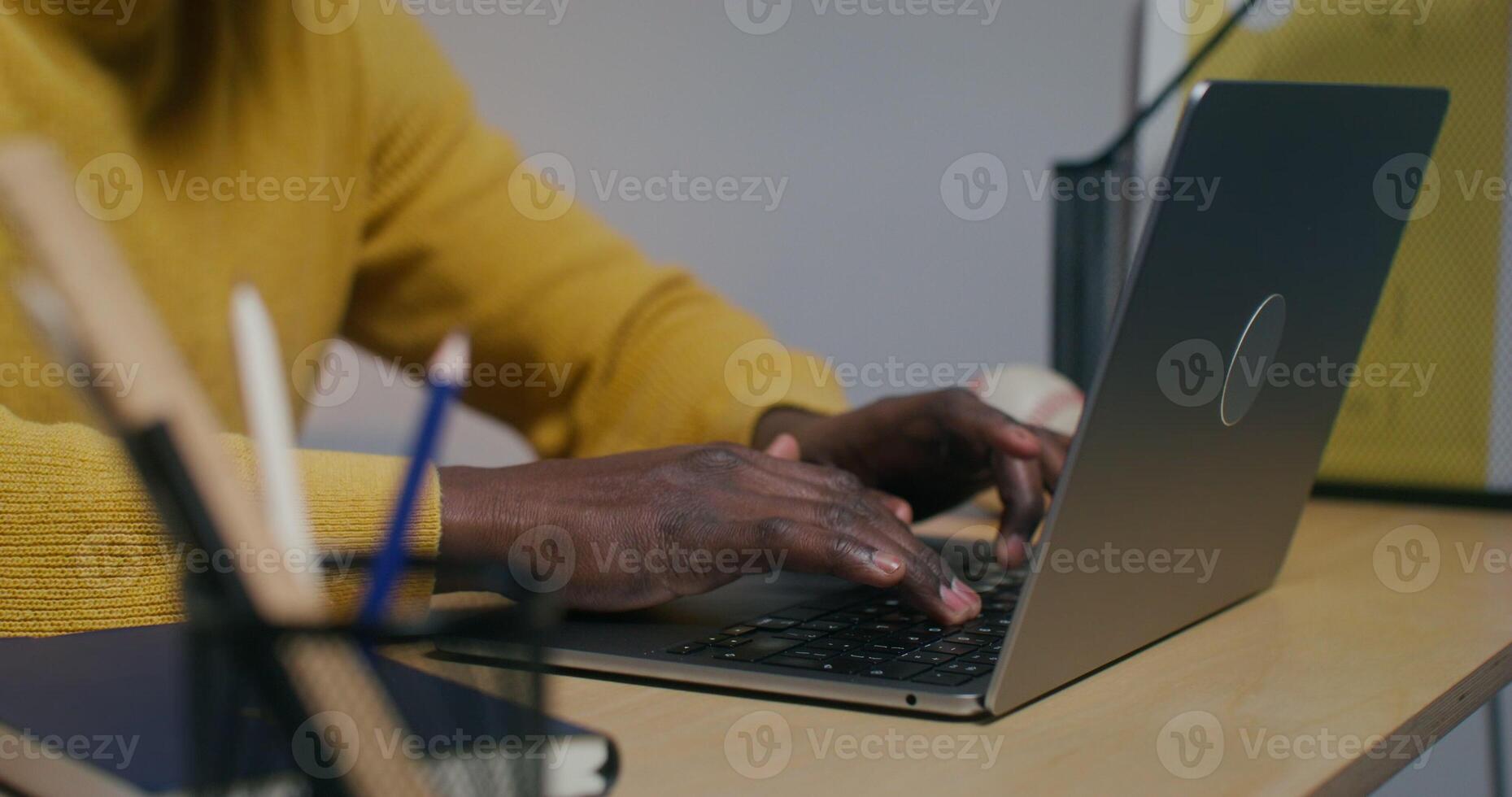 A man typing on a laptop keyboard, sitting at a desk in the office, close-up of his hands - typing photo