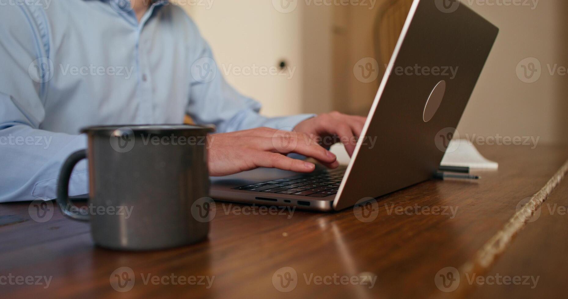 A man uses a laptop sitting at the kitchen table. Close-up of his hands, an unrecognizable person - person photo