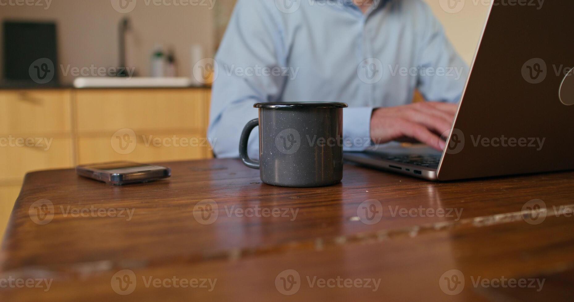 A man uses a laptop sitting at the kitchen table. Close-up of his hands, an unrecognizable person - kitchen photo