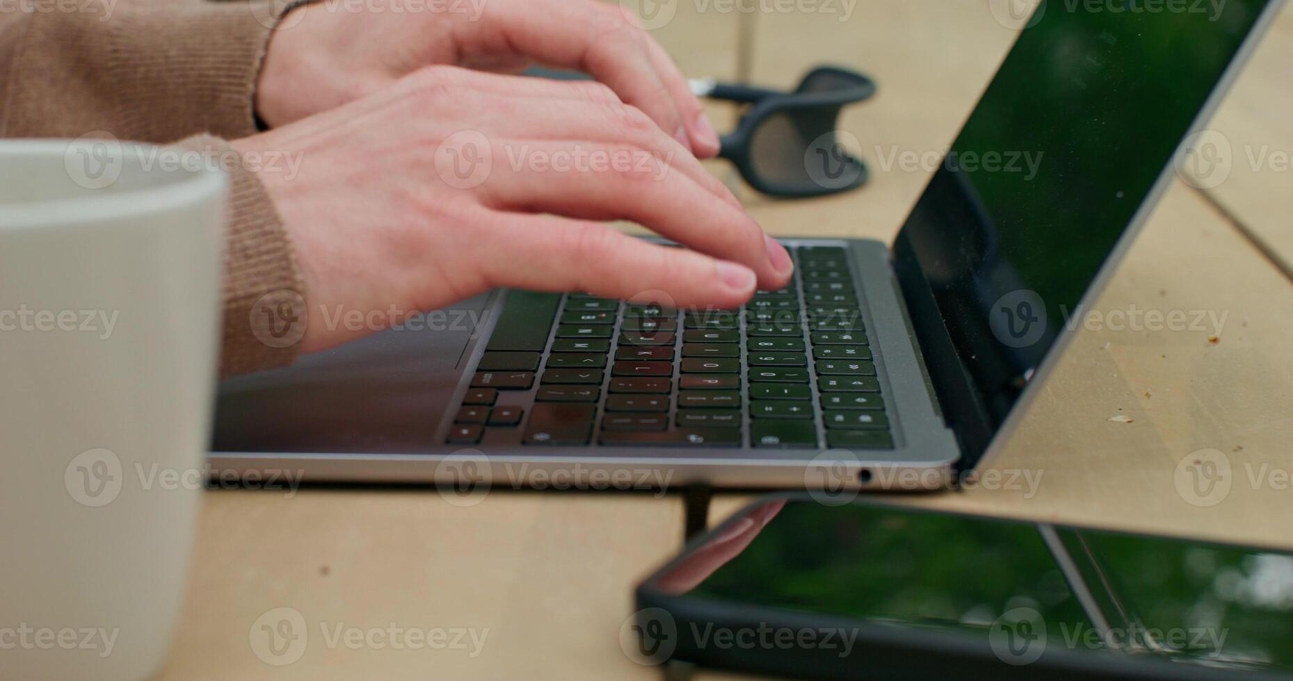 A man is typing on a laptop sitting at a table. Close-up of his hands, an unrecognizable person - unrecognizable photo