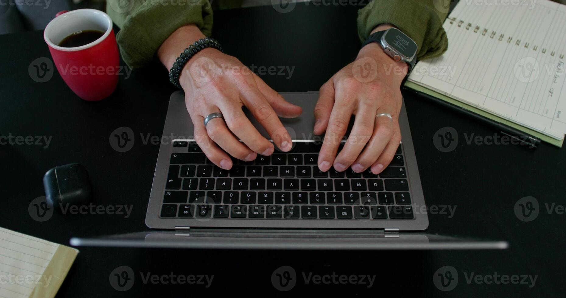 A man in casual clothes is typing on a laptop sitting at a table at home with a serious look. Daylight - typing photo