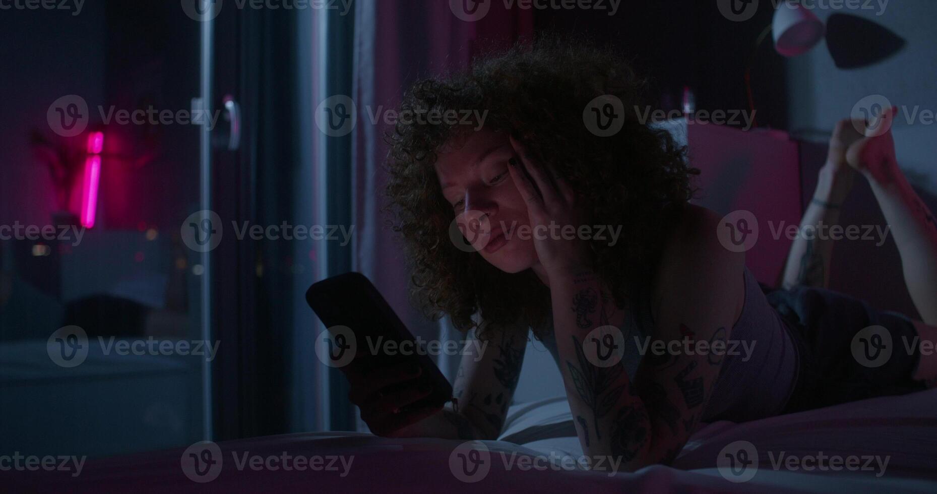 A man uses a mobile phone lying on the bed. Dark room, home interior - mobile - a photo