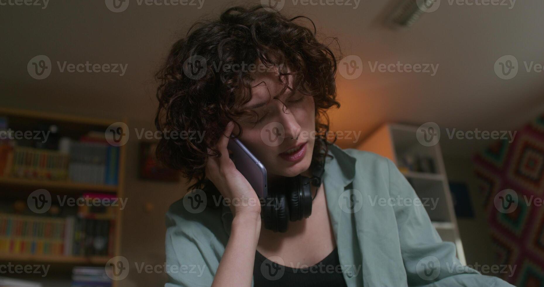 A young woman is talking on a mobile phone sitting at home with a sad look - sitting photo