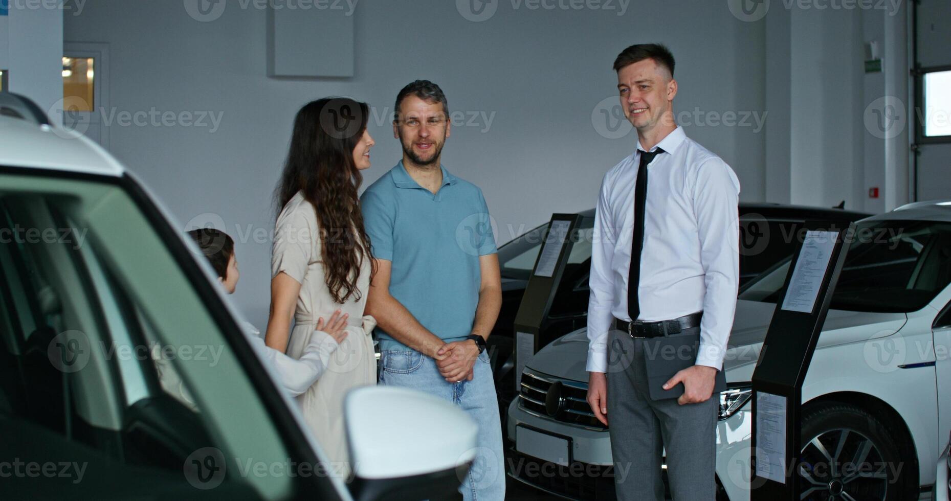 A man and woman standing next to a car in a showroom photo