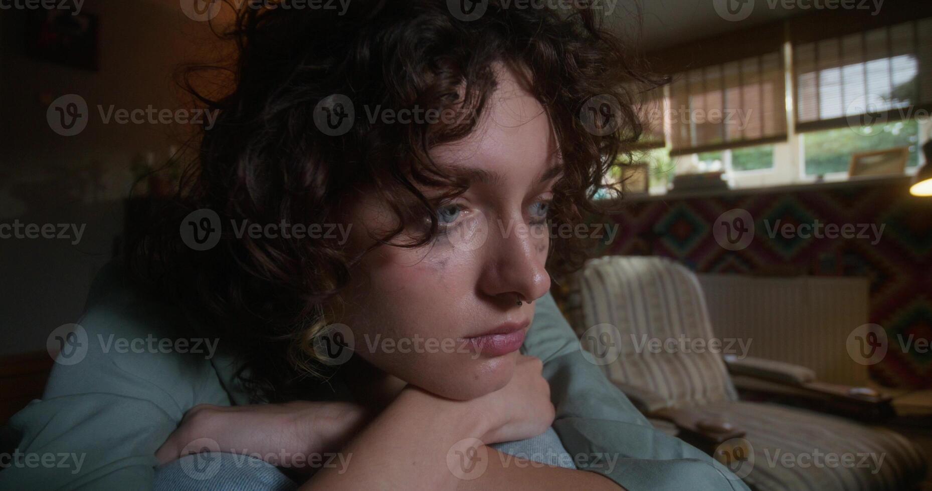 A woman is crying sitting on a bed at home. Mascara is smeared under her eyes. Depression, broken heart - Mascara photo