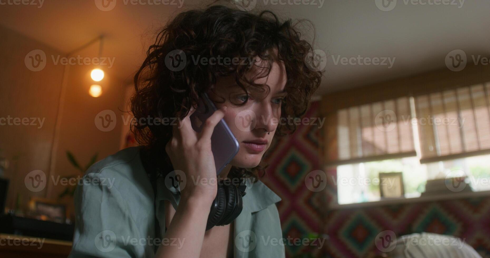 A young woman is talking on a mobile phone sitting at home with a sad look photo