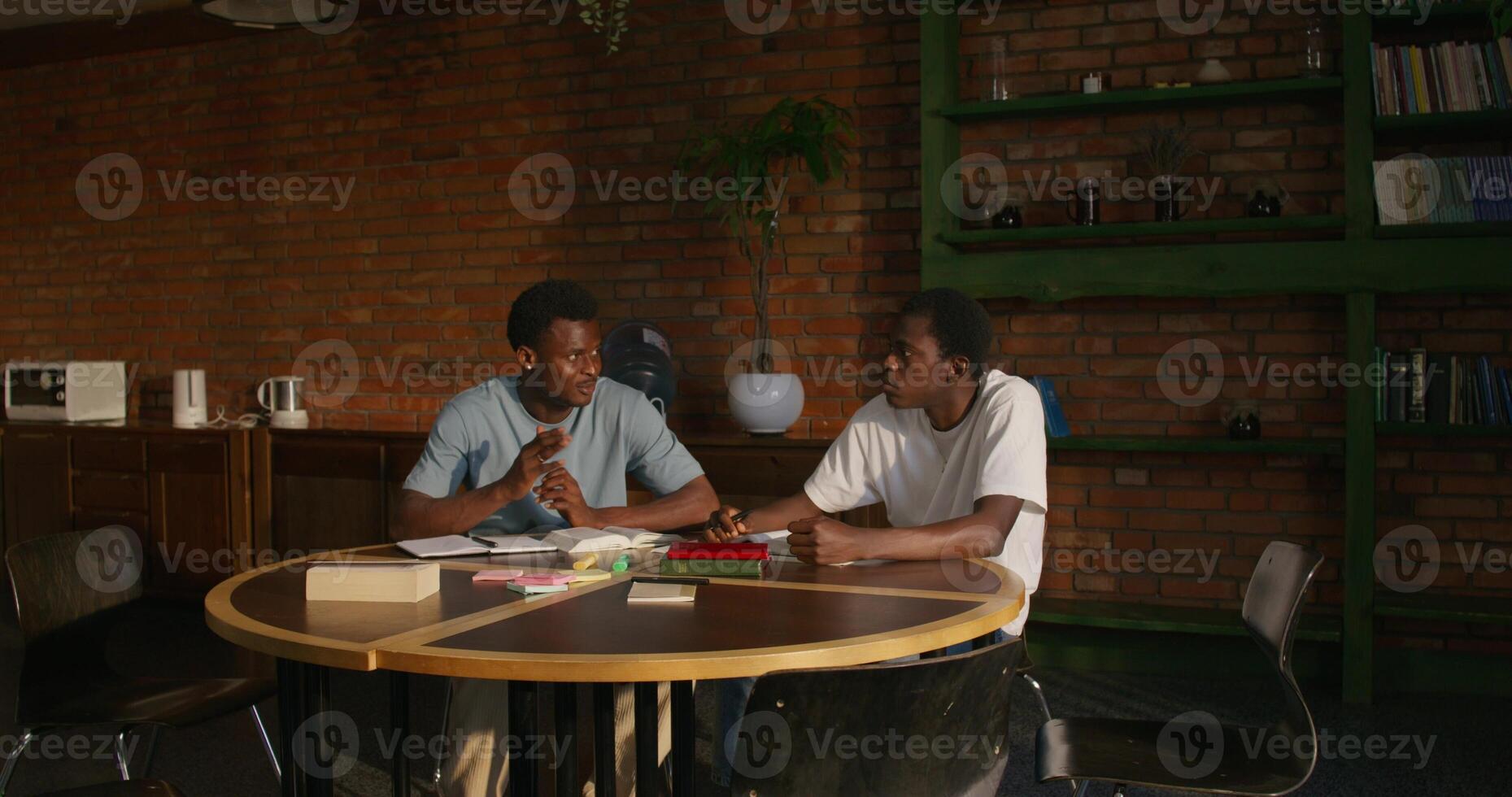 Two men are talking while studying the Bible together. They are sitting at the table indoors - sitting photo