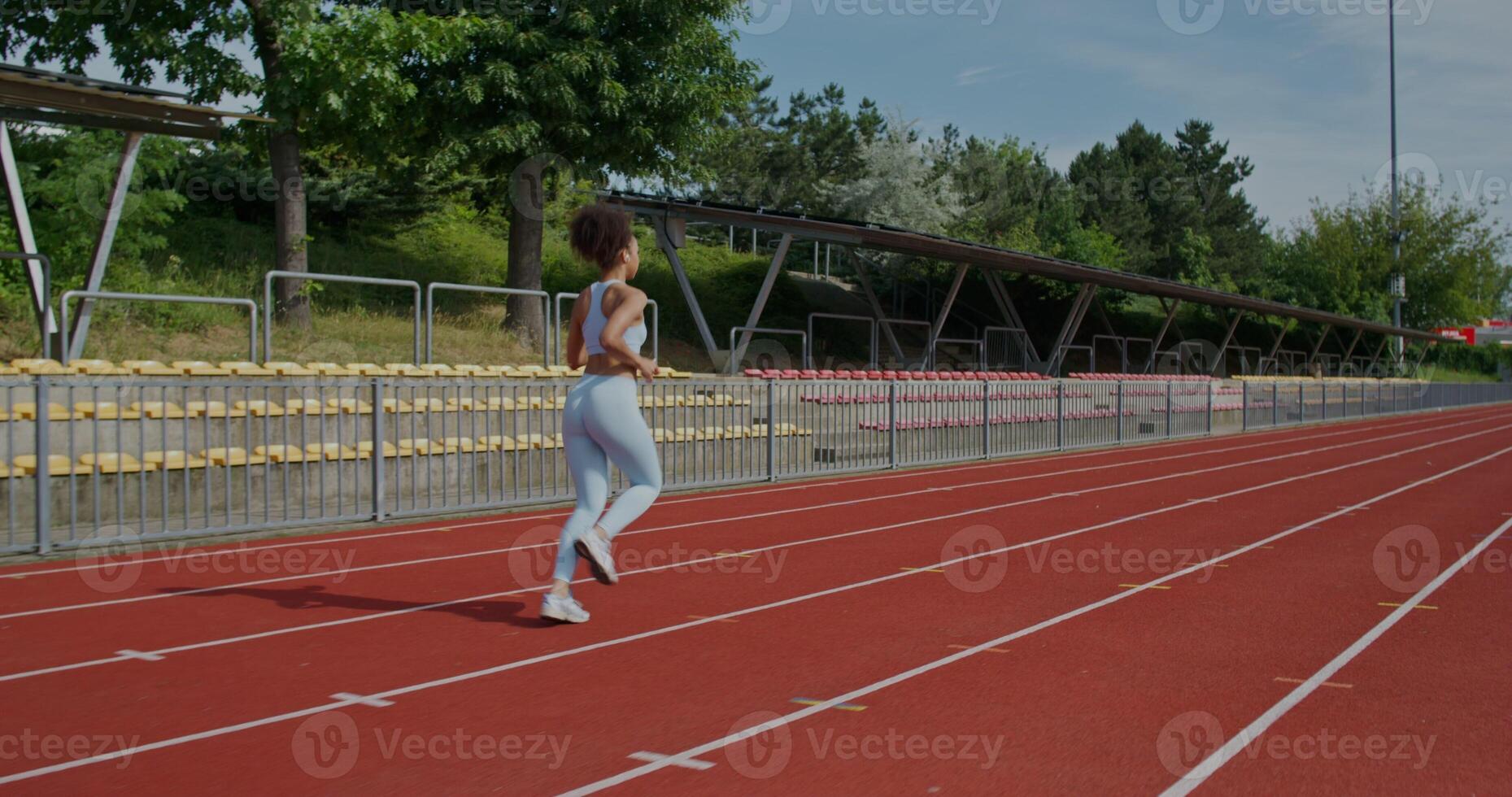 A woman in sports clothes running at the stadium on a summer day, rear view, unrecognizable person photo