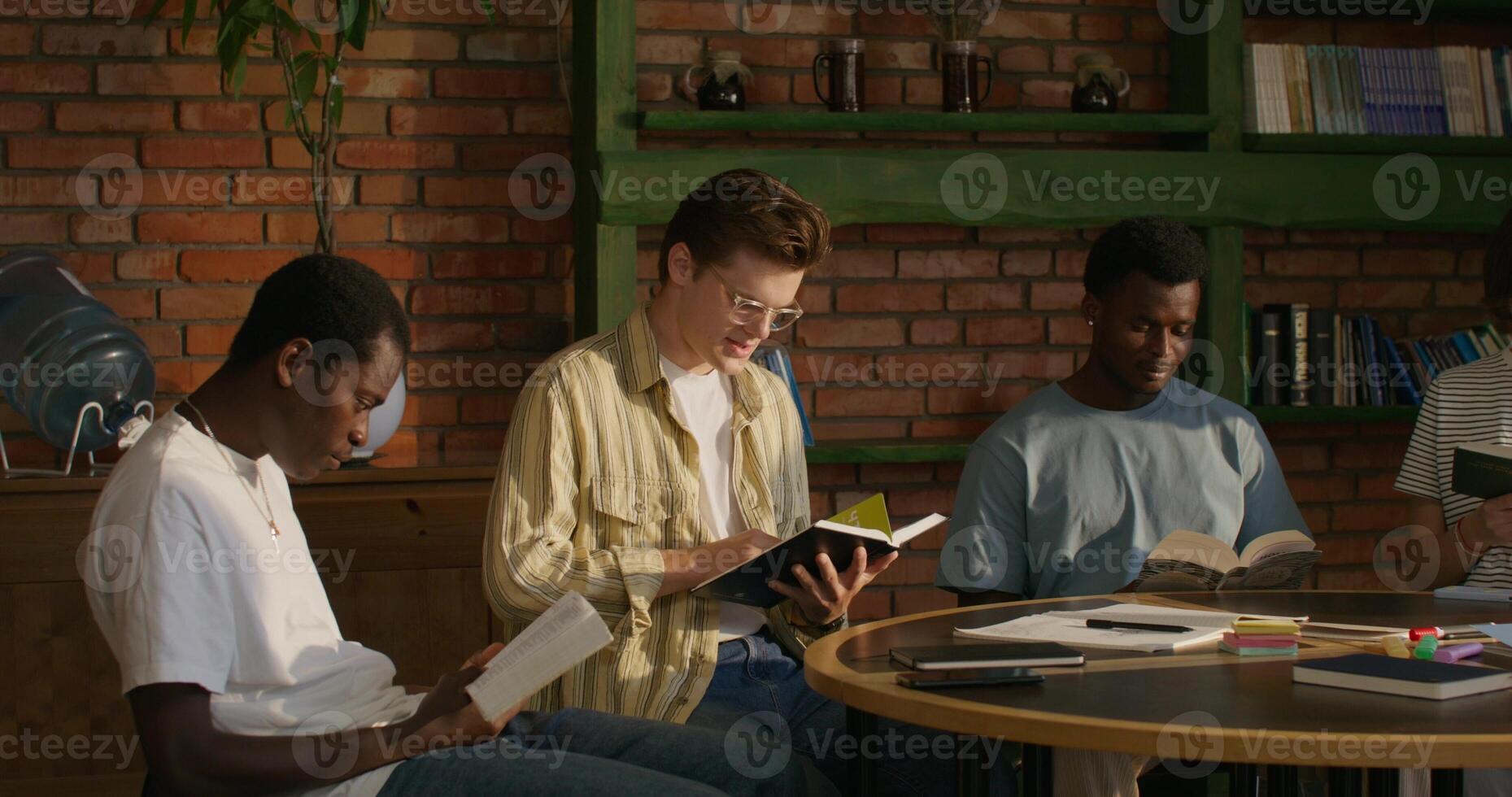 A group of young people of different nationalities join hands and begin prayer while sitting at a table indoors. Daylight - nationalities photo